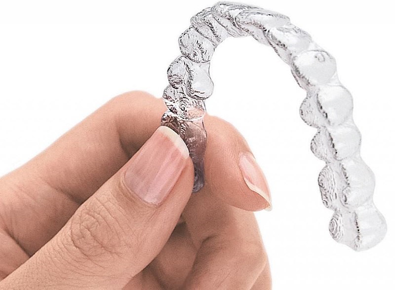 clear braces held by a hand