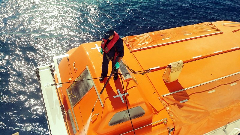 ship worker cleaning lifeboat