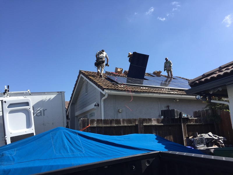 workers installing solar panels on home rooftop